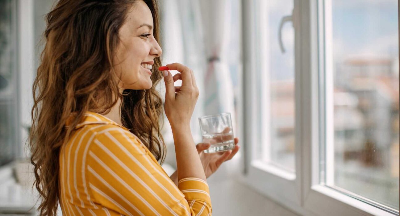 Kobieta przyjmująca suplement diety w domowym otoczeniu