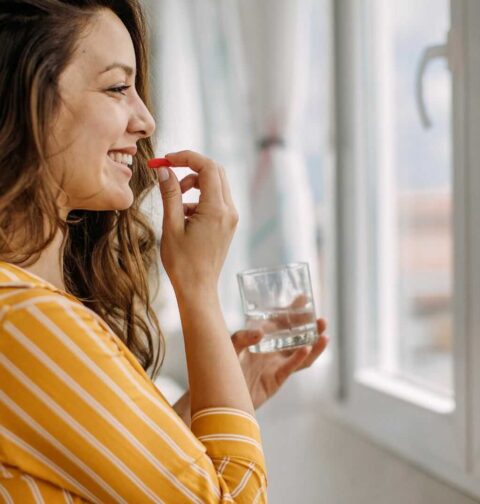 Kobieta przyjmująca suplement diety w domowym otoczeniu