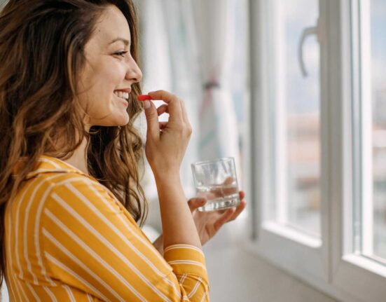 Kobieta przyjmująca suplement diety w domowym otoczeniu